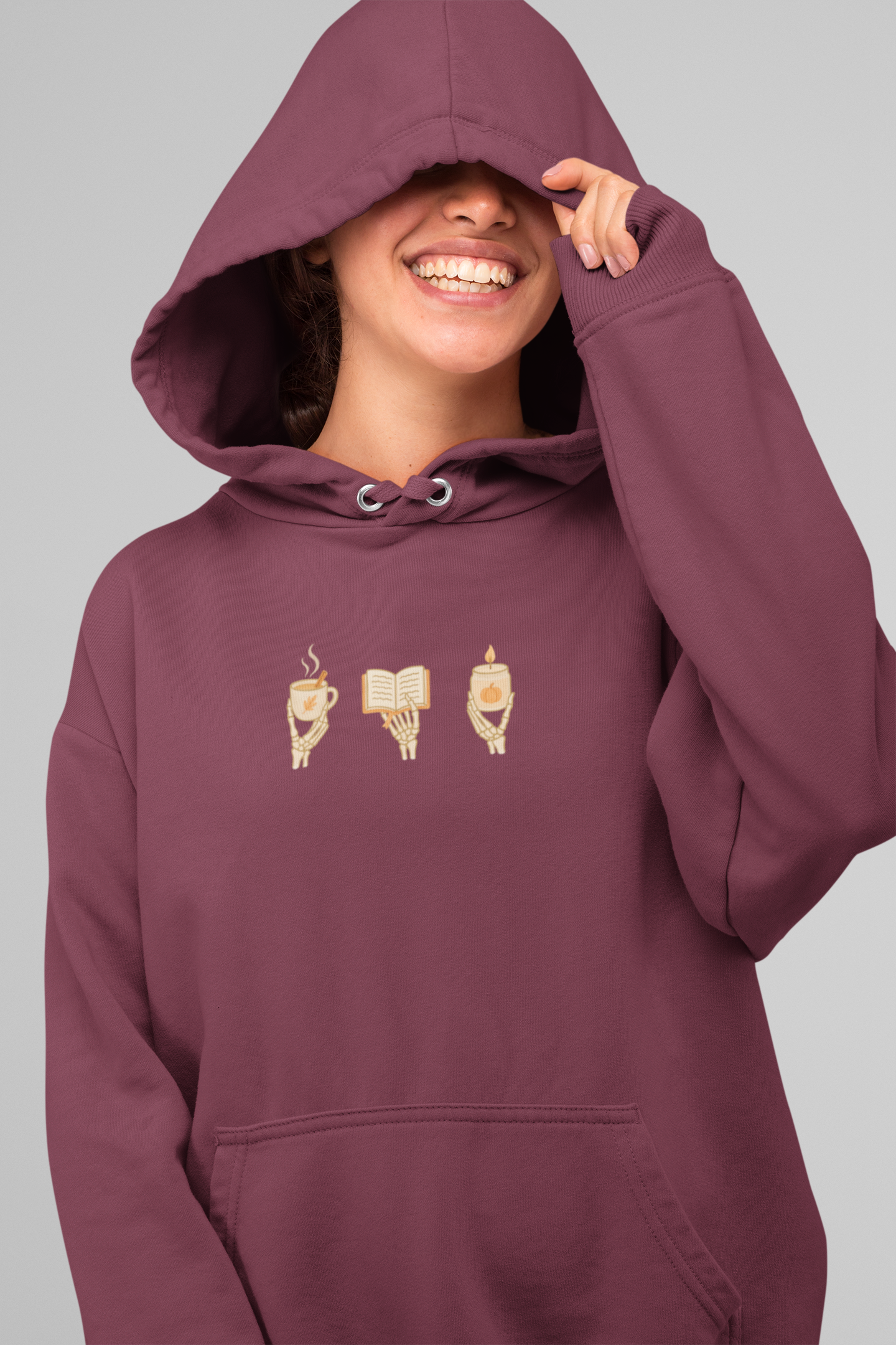 Adult hoodie in maroon with 'Cozy Bones' graphic print. Fall & halloween themed graphic sweatshirts. 
