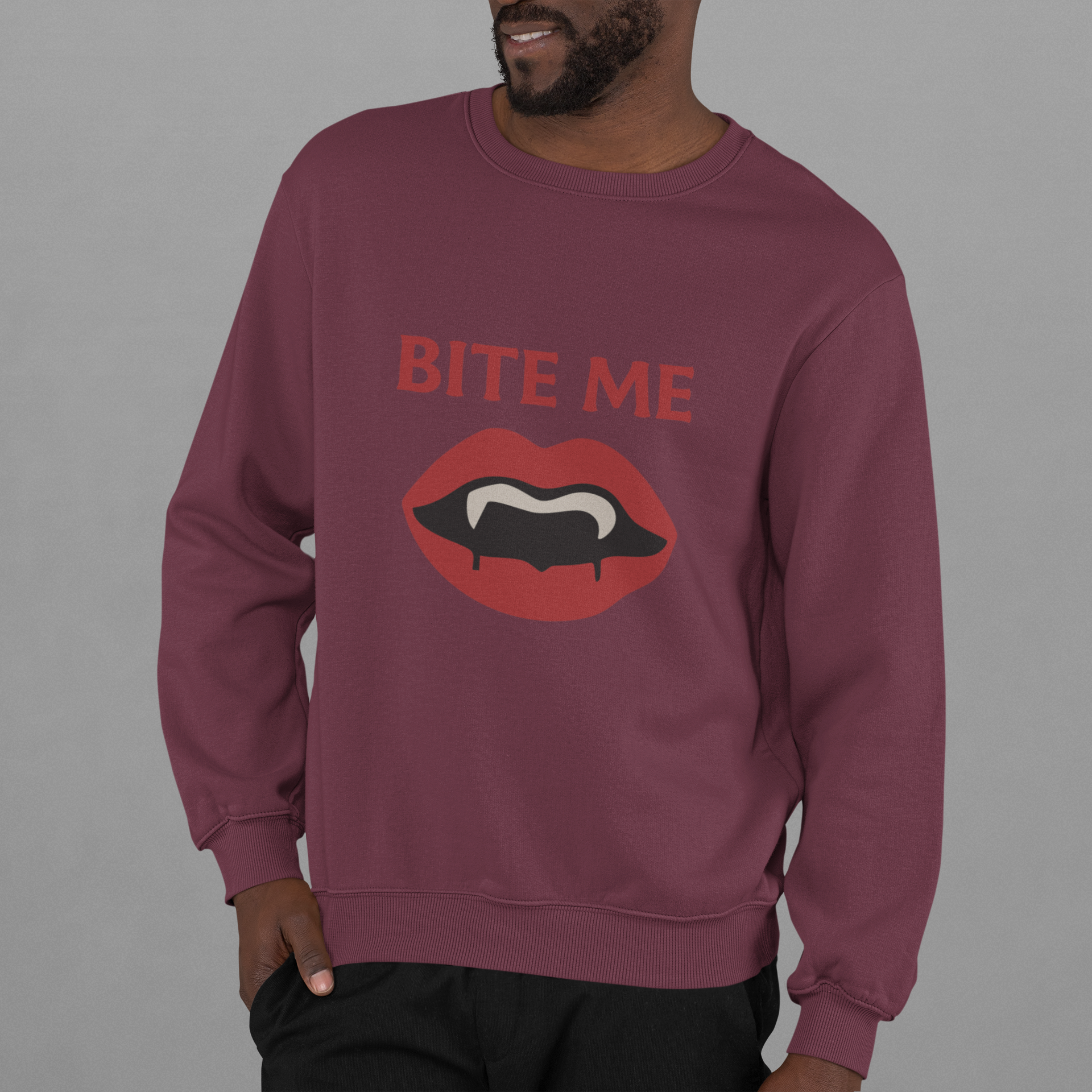 Adult sweatshirt in maroon with 'Bite Me' graphic print with vampire fangs. Funny halloween themed graphic tees. 