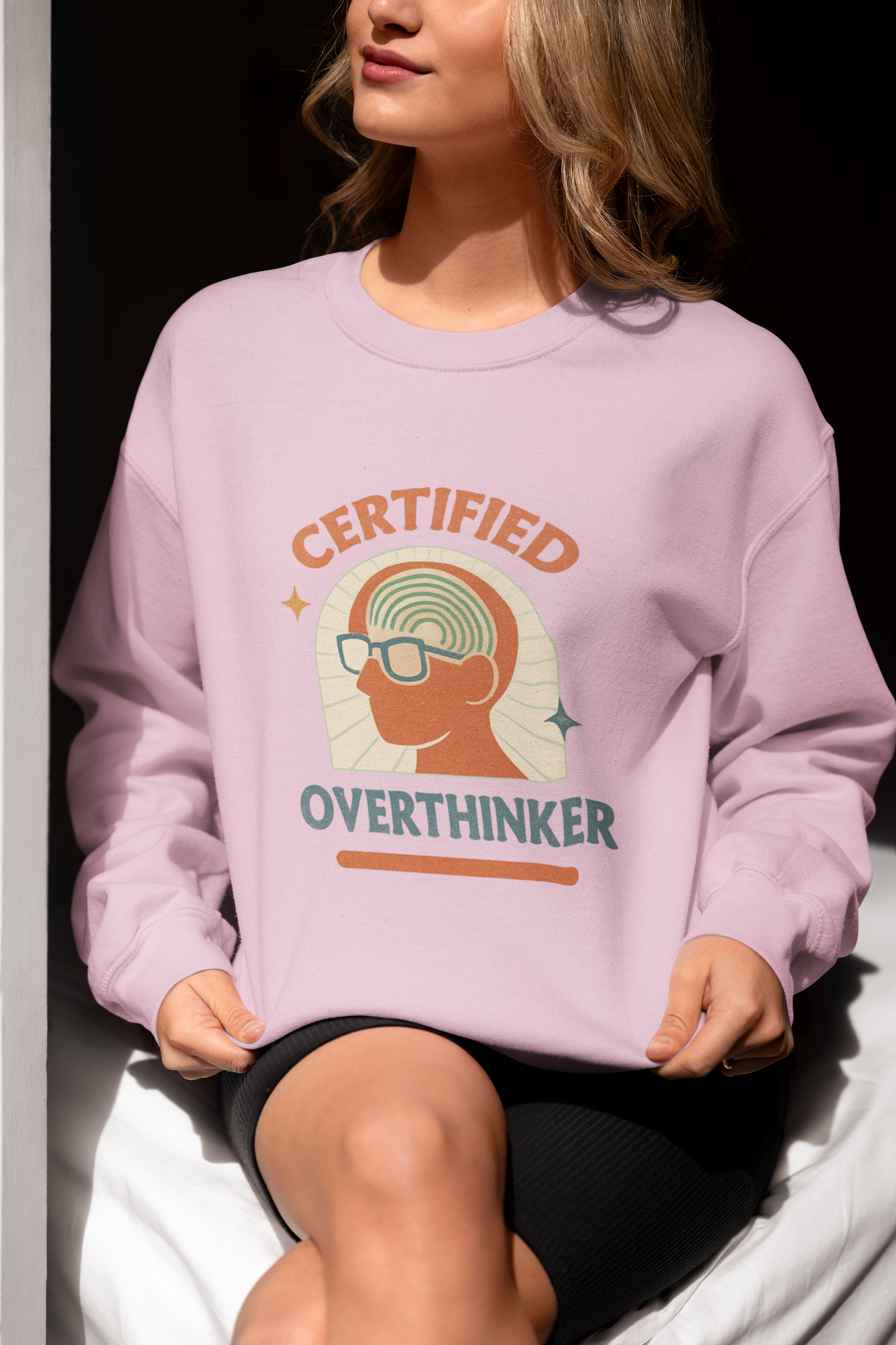 Light pink unisex crewneck sweatshirt with retro Certified Overthinker graphic, featuring silhouette head with spiral brain and glasses.